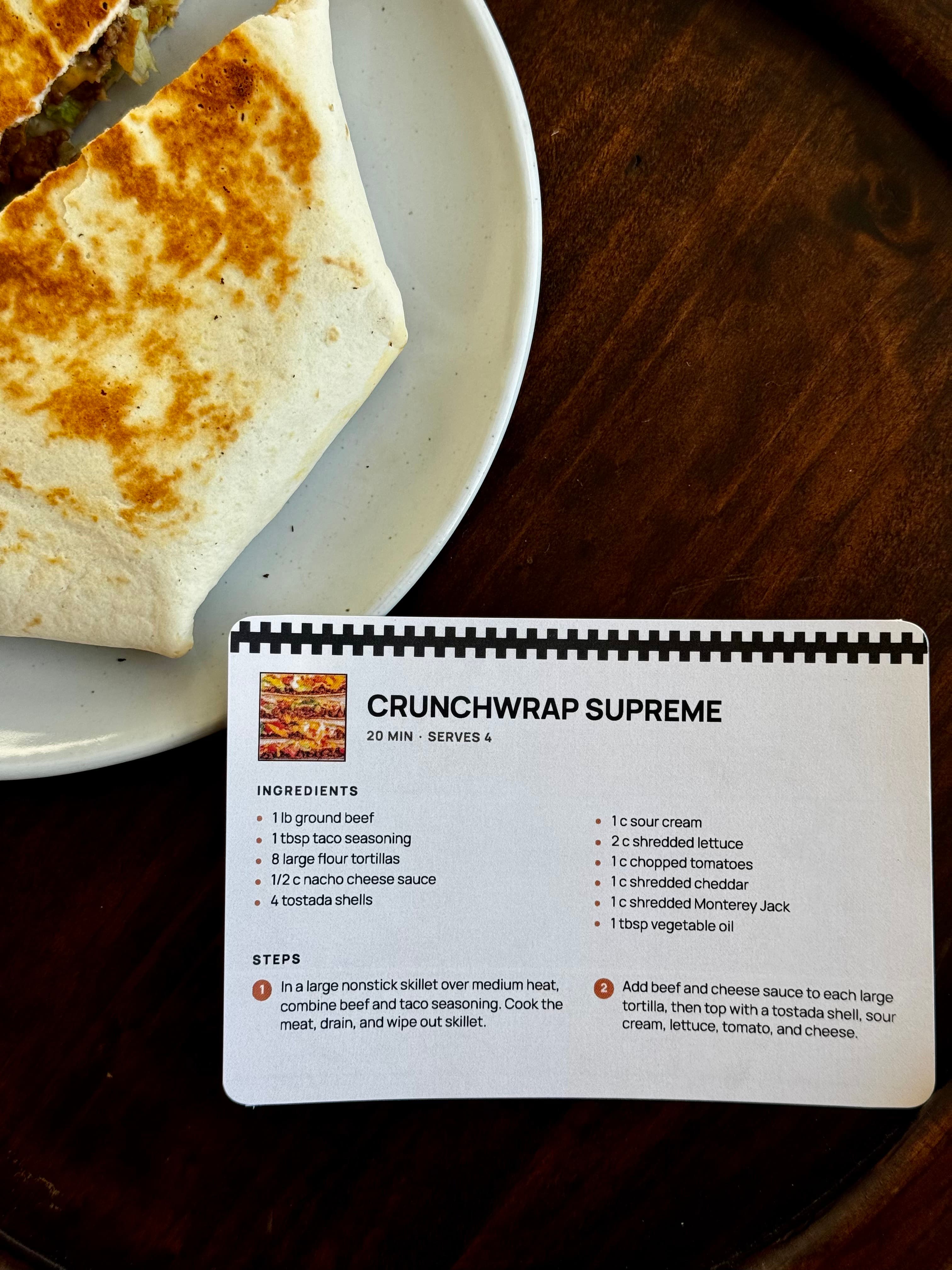 A printed Crunchwrap Supreme recipe card beside the finished crunchwrap.